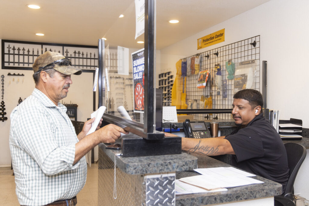 A man conversing with a customer behind the counter at Eagle National Steel