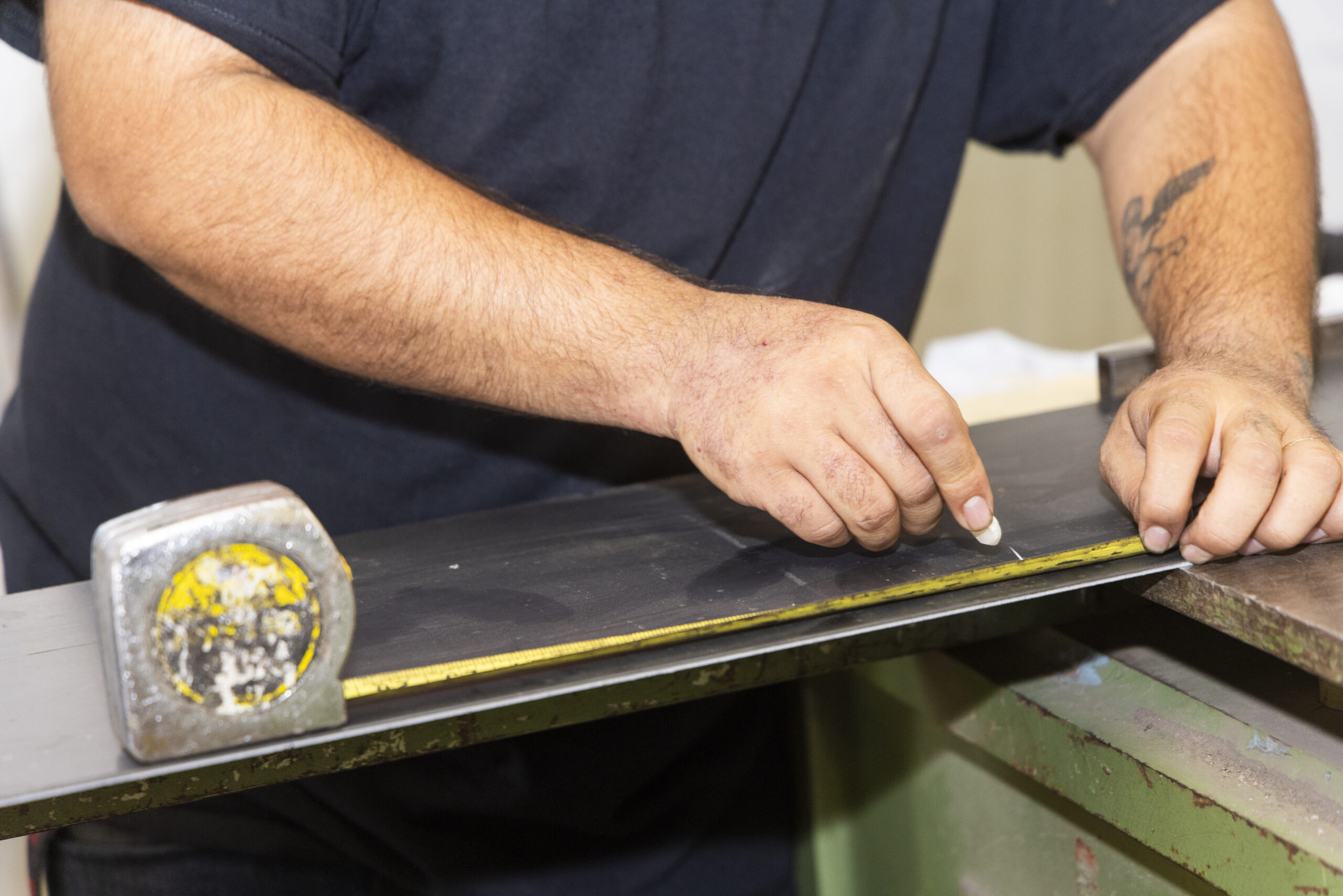 A man measuring and marking steel